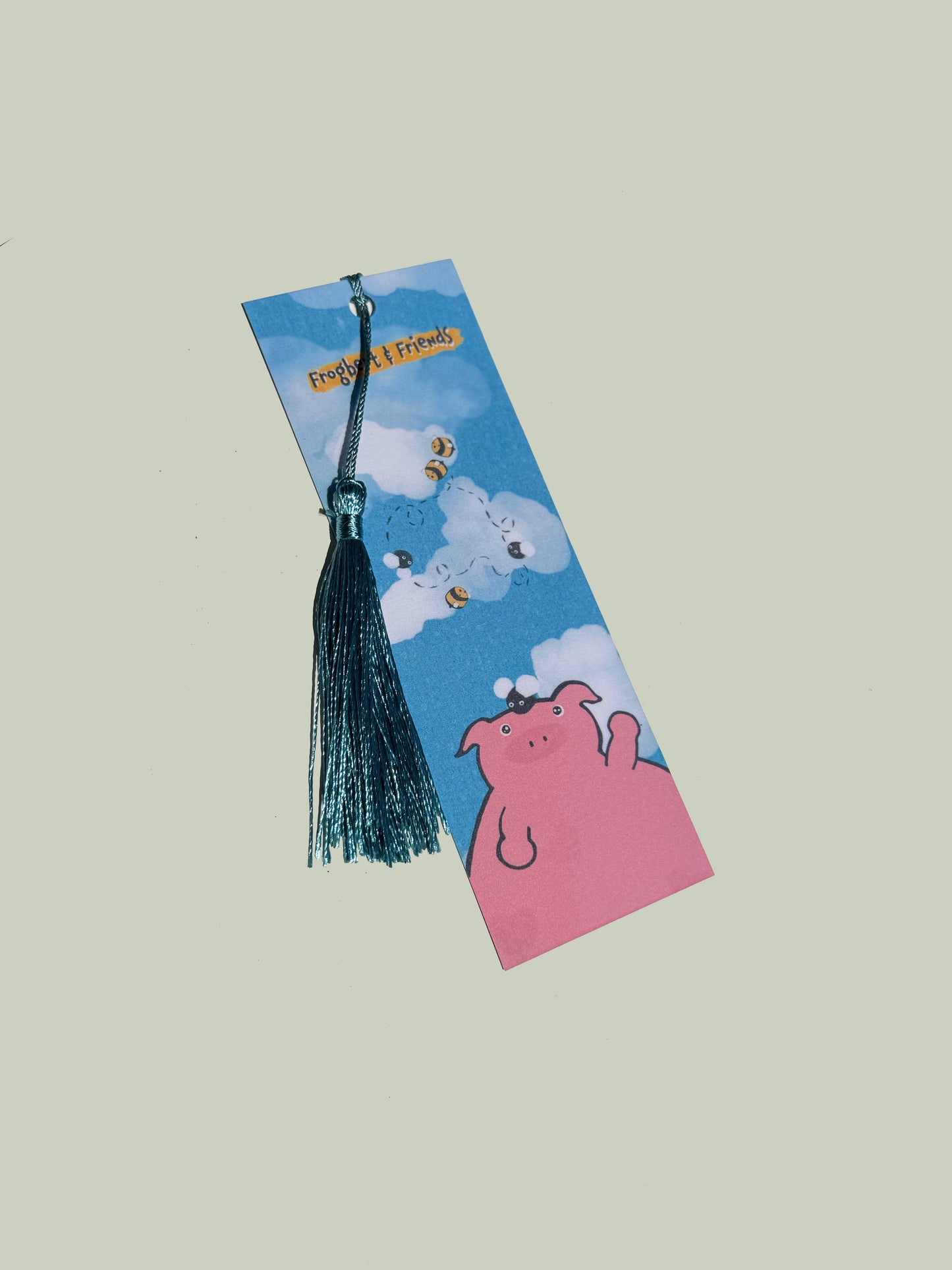 Bookmark with cartoon design featuring a pig and tassel on a light gray background
