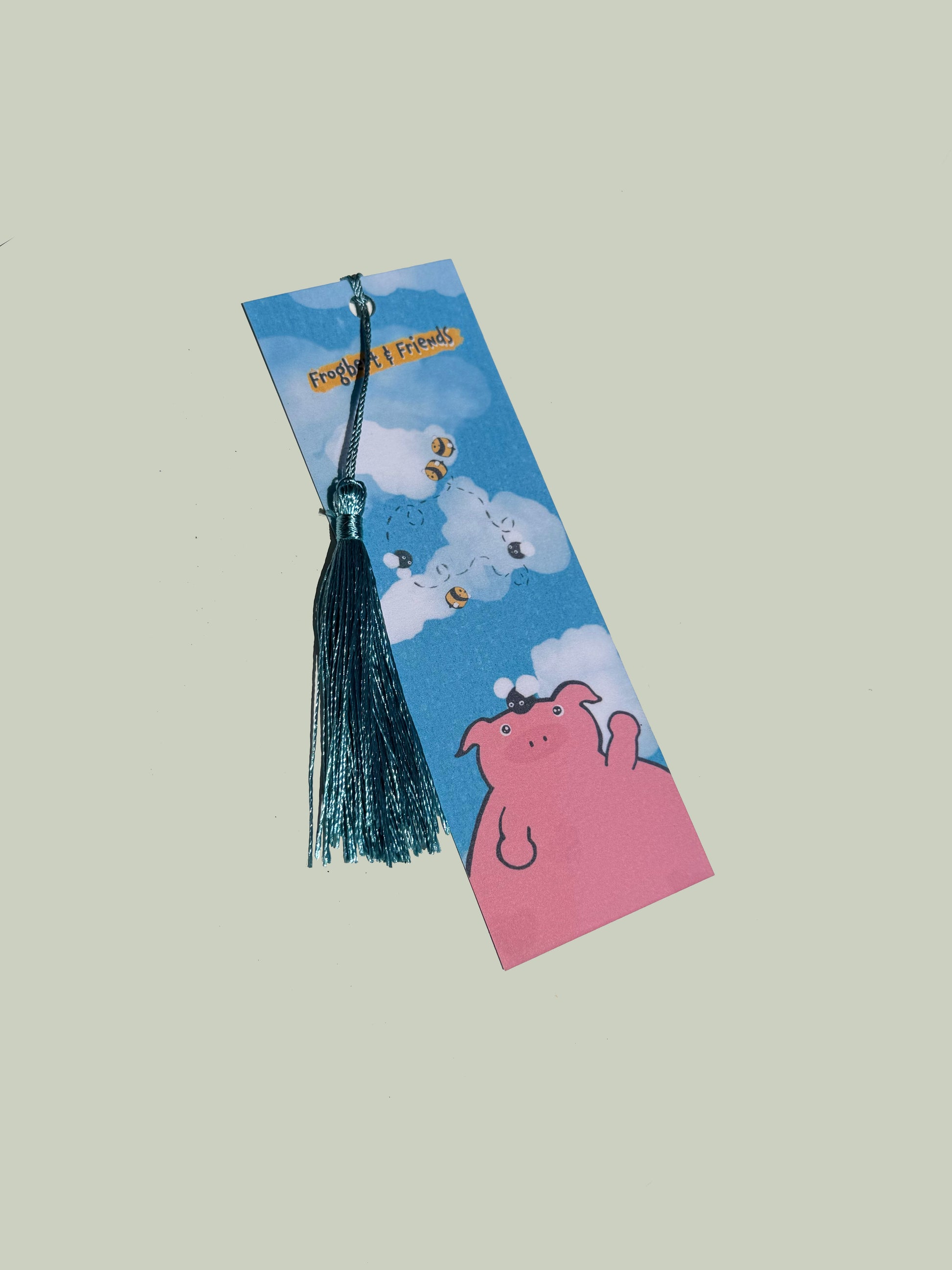 Bookmark with cartoon design featuring a pig and tassel on a light gray background